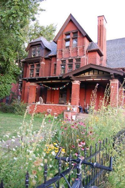 Victorian-style red brick house with garden and bicycle in front.