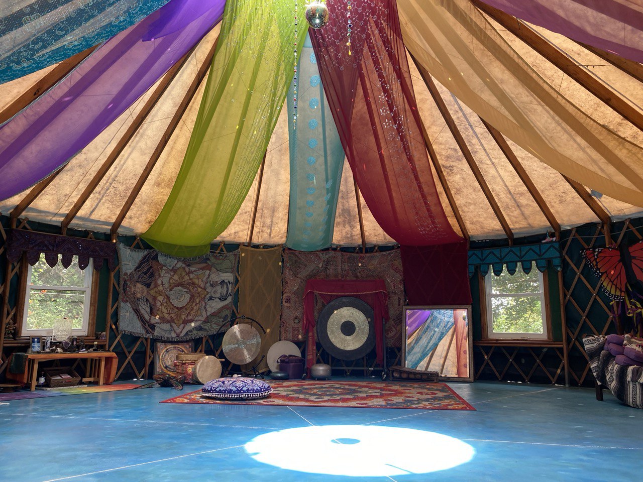 Vibrant fabric drapes inside a community yurt with musical instruments and decor.