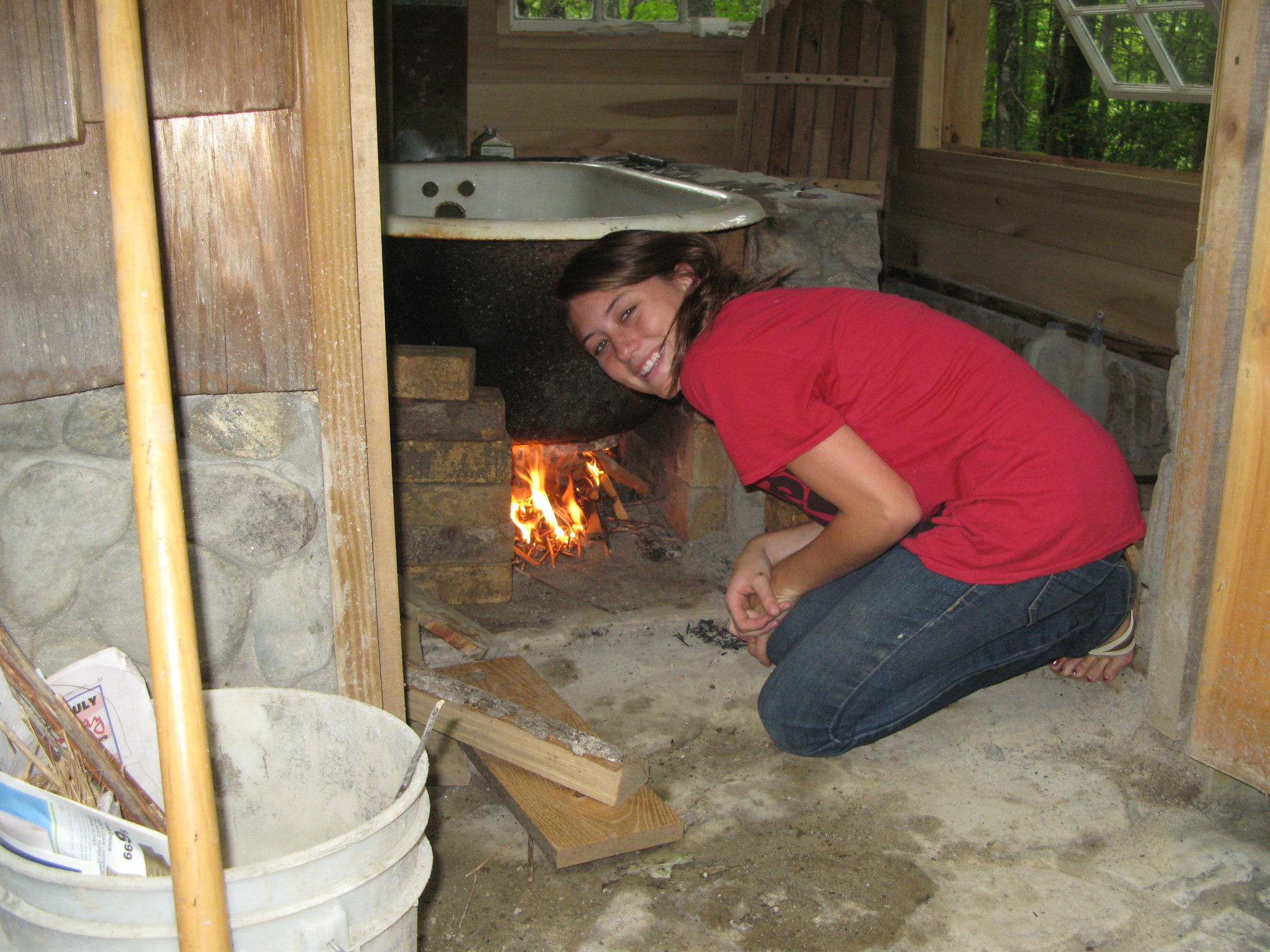 Woman kneeling by an outdoor fire pit at Coweeta Heritage Center.