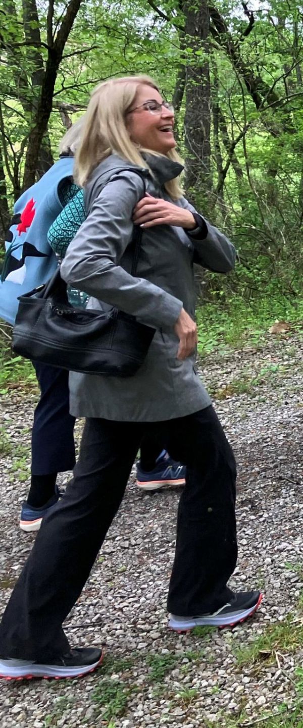 Woman hiking in a lush green forest with a backpack.