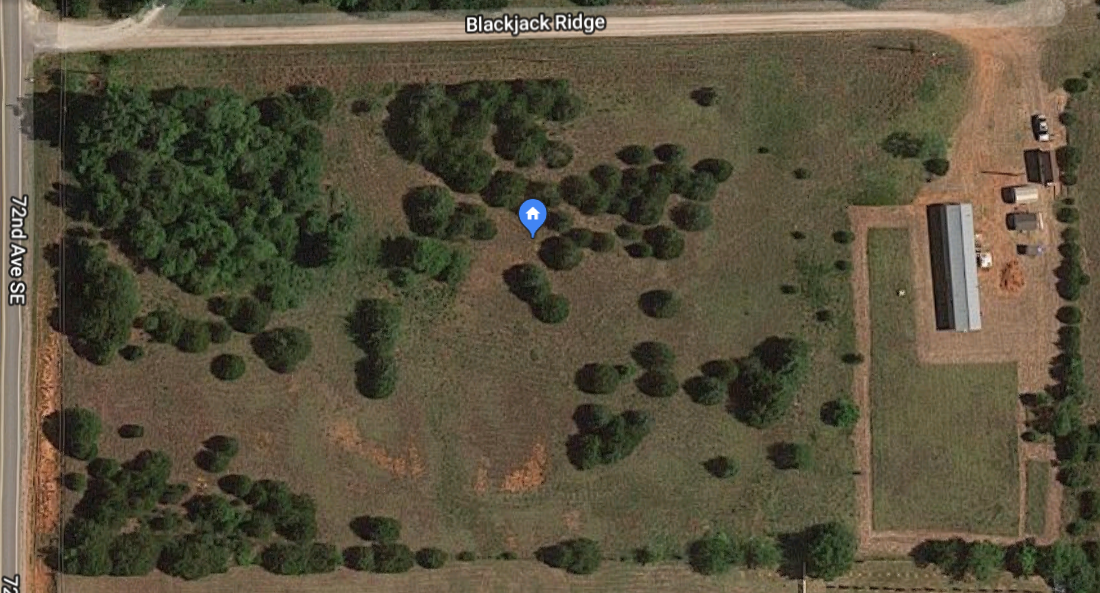 Aerial view of a community garden with trees, pathways, and a building.
