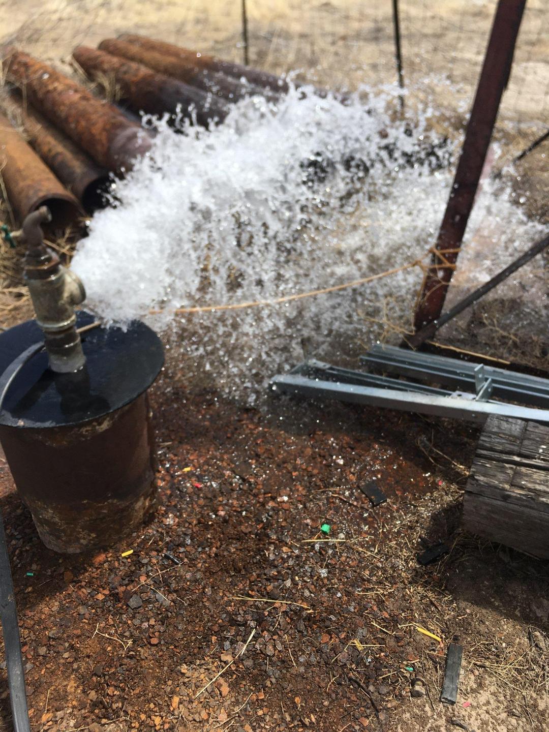 Water spraying from irrigation pipe on community farm.