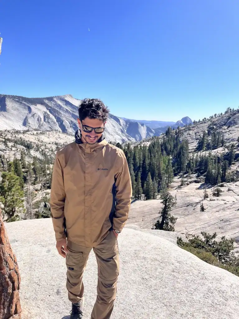 Man hiking in Yosemite with mountains and trees in background.