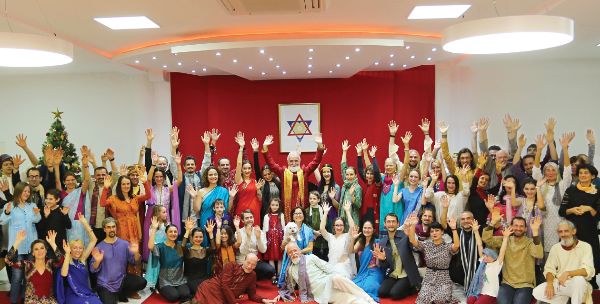 Large diverse group of people celebrating in a community center with a Star of David symbol.