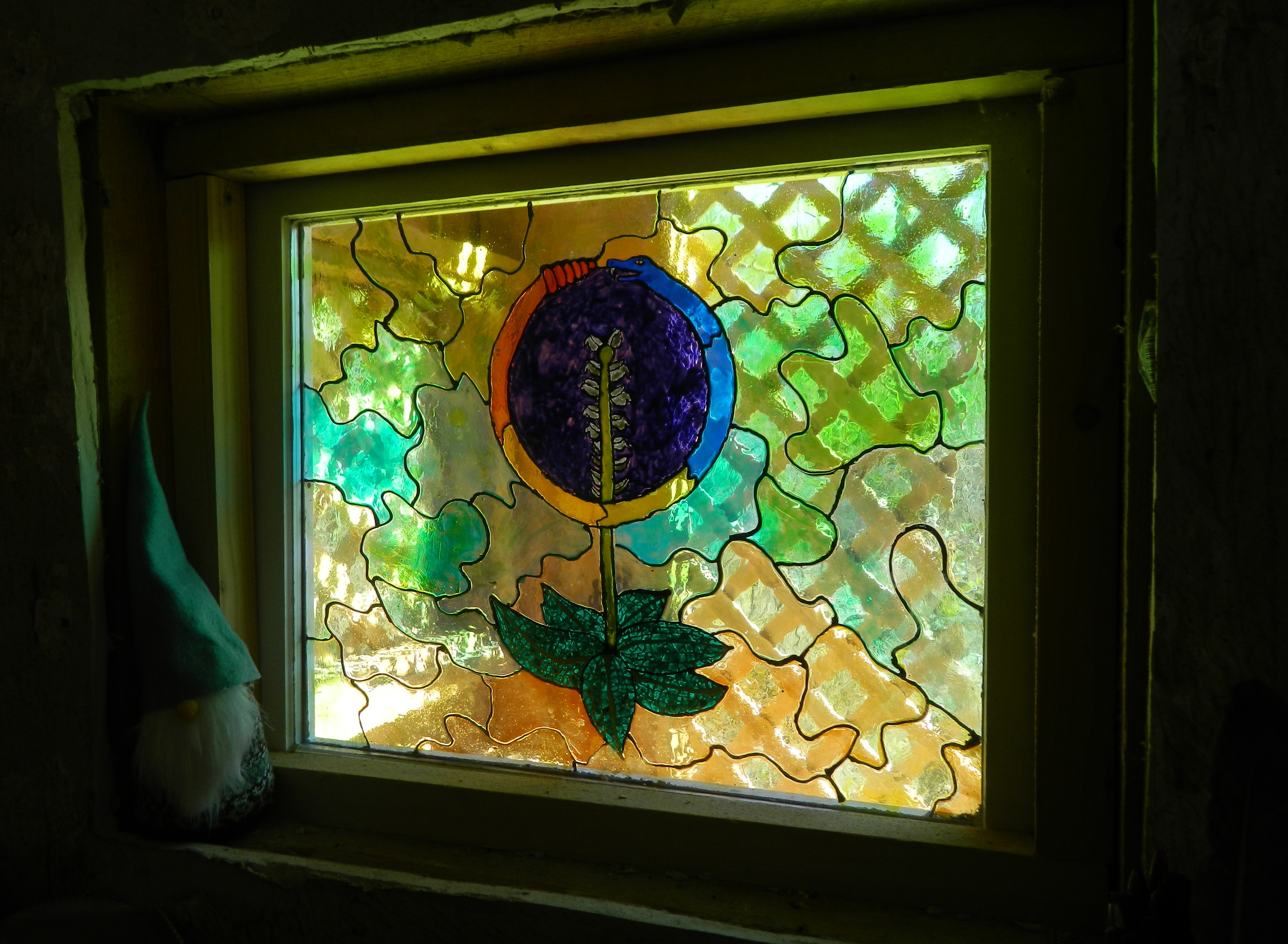 Vibrant stained glass window featuring a plant motif and abstract background.