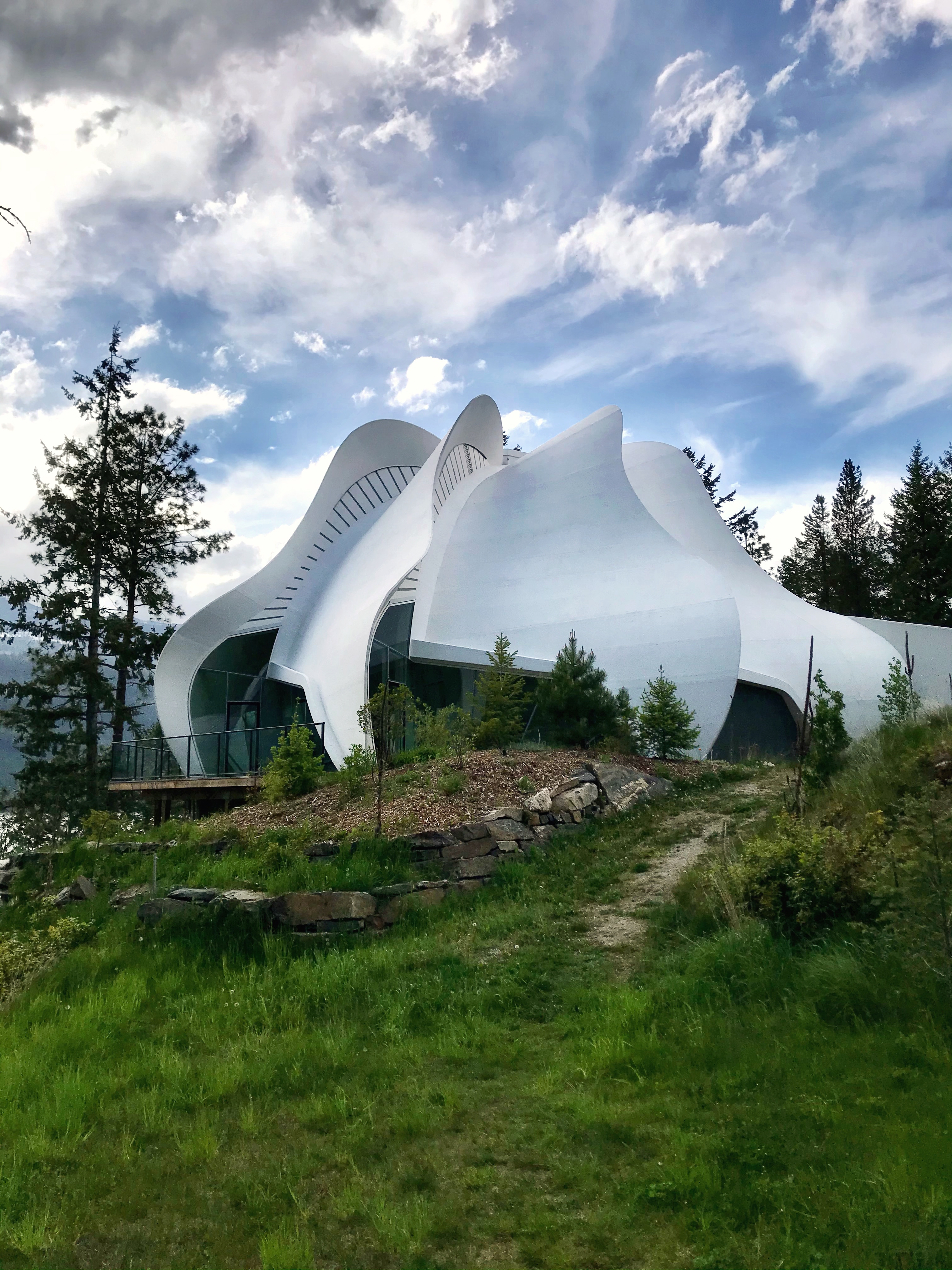 Unique modern architectural building with flowing white curves in a natural setting.