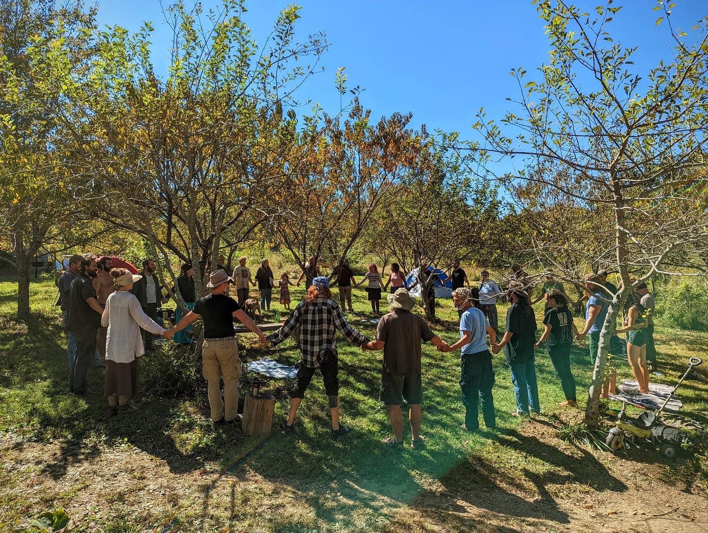 People holding hands in a circle during outdoor community event at The Garden.