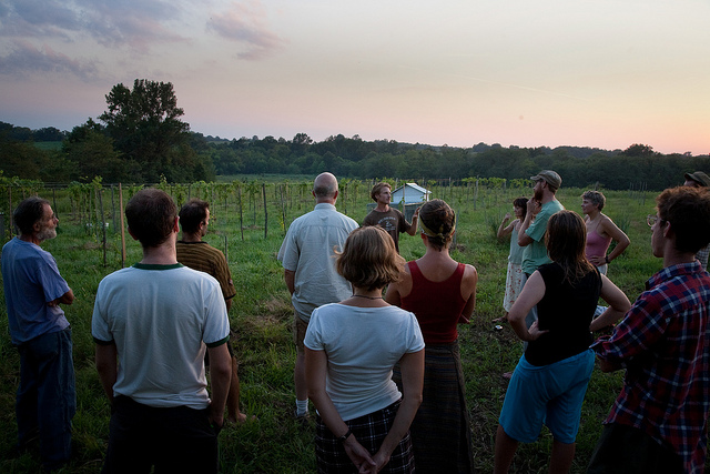 Group of people gathered outdoors at sunset in a community setting.
