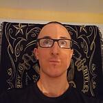 Person with glasses in front of Foundation for Intentional Community banner.