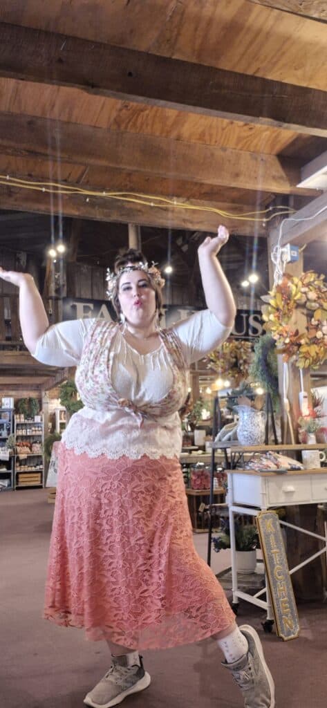Woman with arms raised in a cozy, rustic community space.