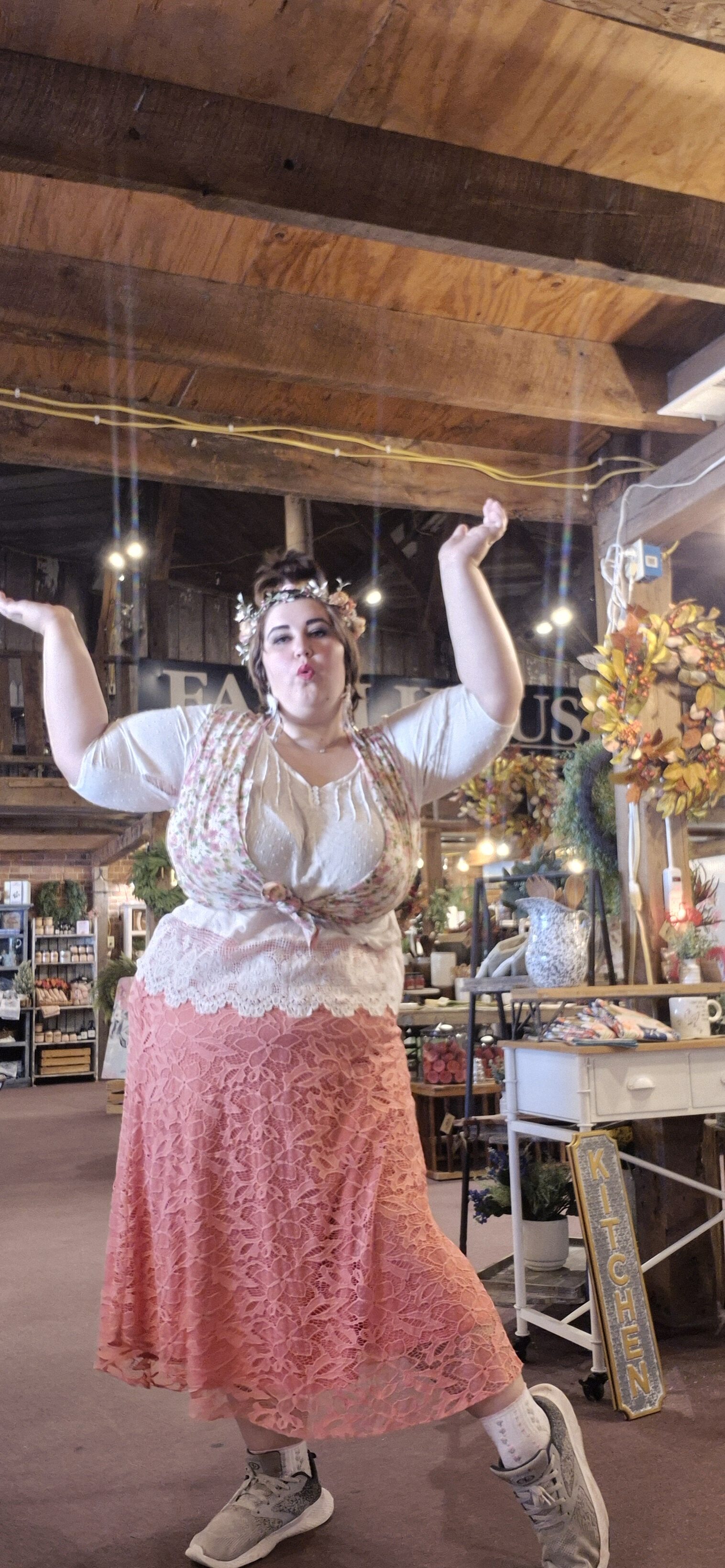 Woman with arms raised in a cozy, rustic community space.