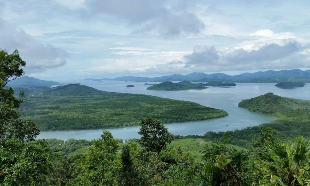 Panoramic view of lush green landscape and water bodies in Bloom Village, South Thailand.