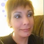 Person with short hair and a playful expression, casual setting.