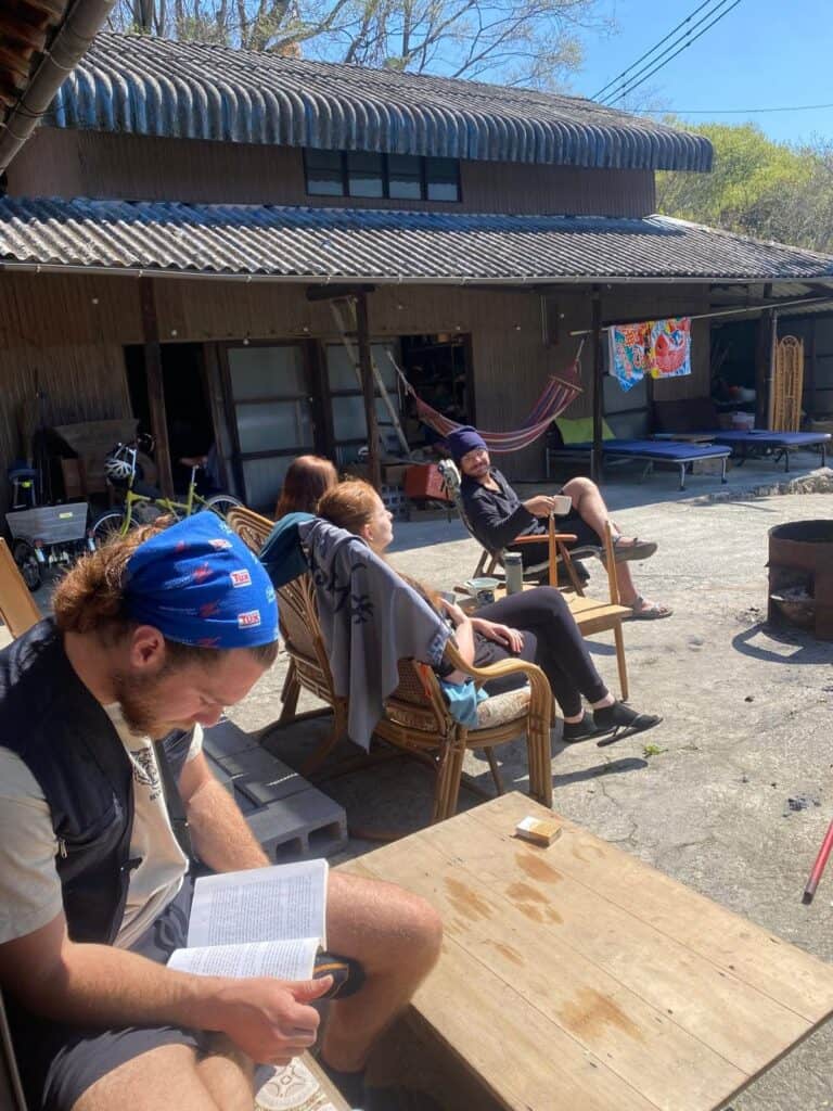 People relaxing outdoors at a community gathering in front of a house.