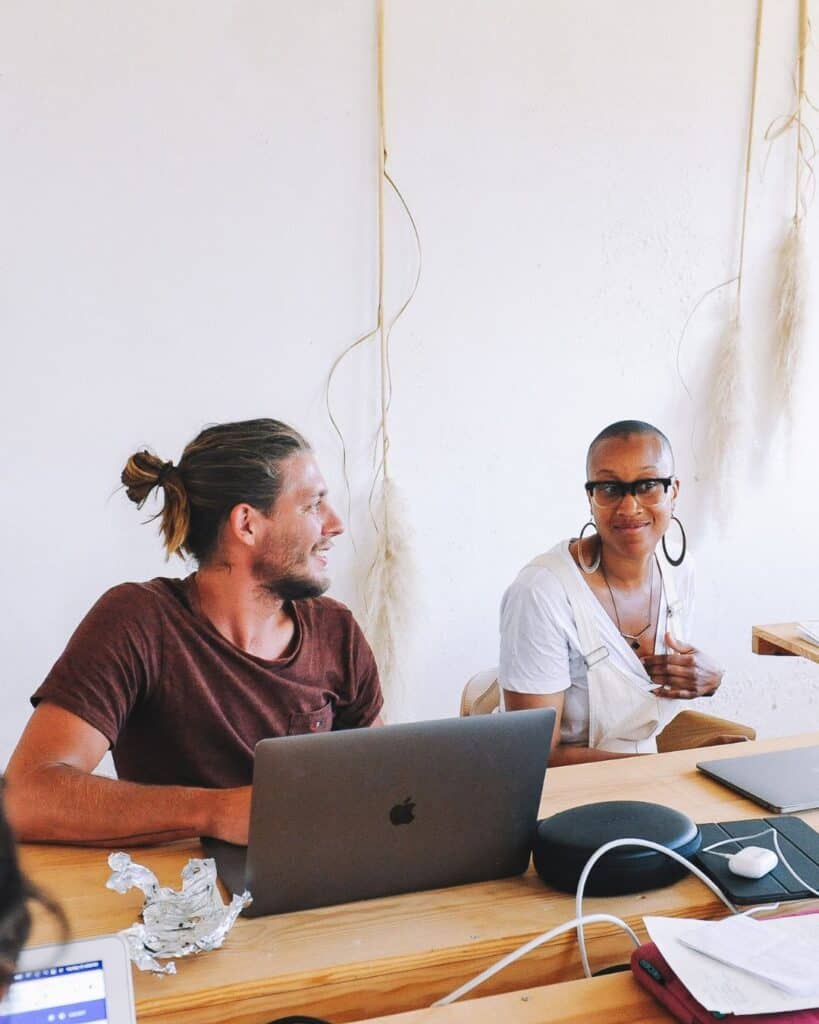 Diverse group of people working together at a table with laptops and documents.