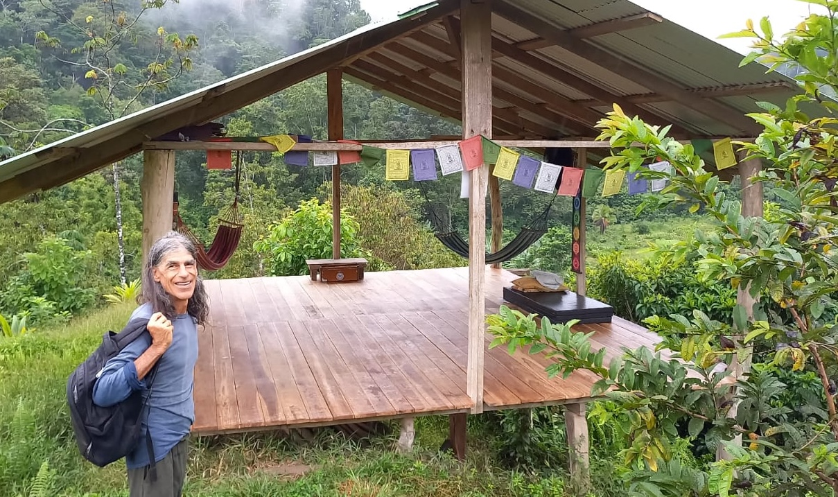 Woman with backpack at eco community stage in lush green landscape.