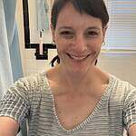 Smiling woman in bathroom with mirror and candles for community website.