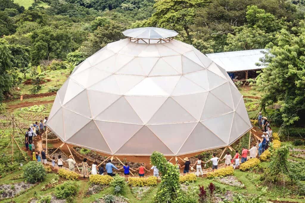Large geodesic dome used as community gathering space in a lush green setting.