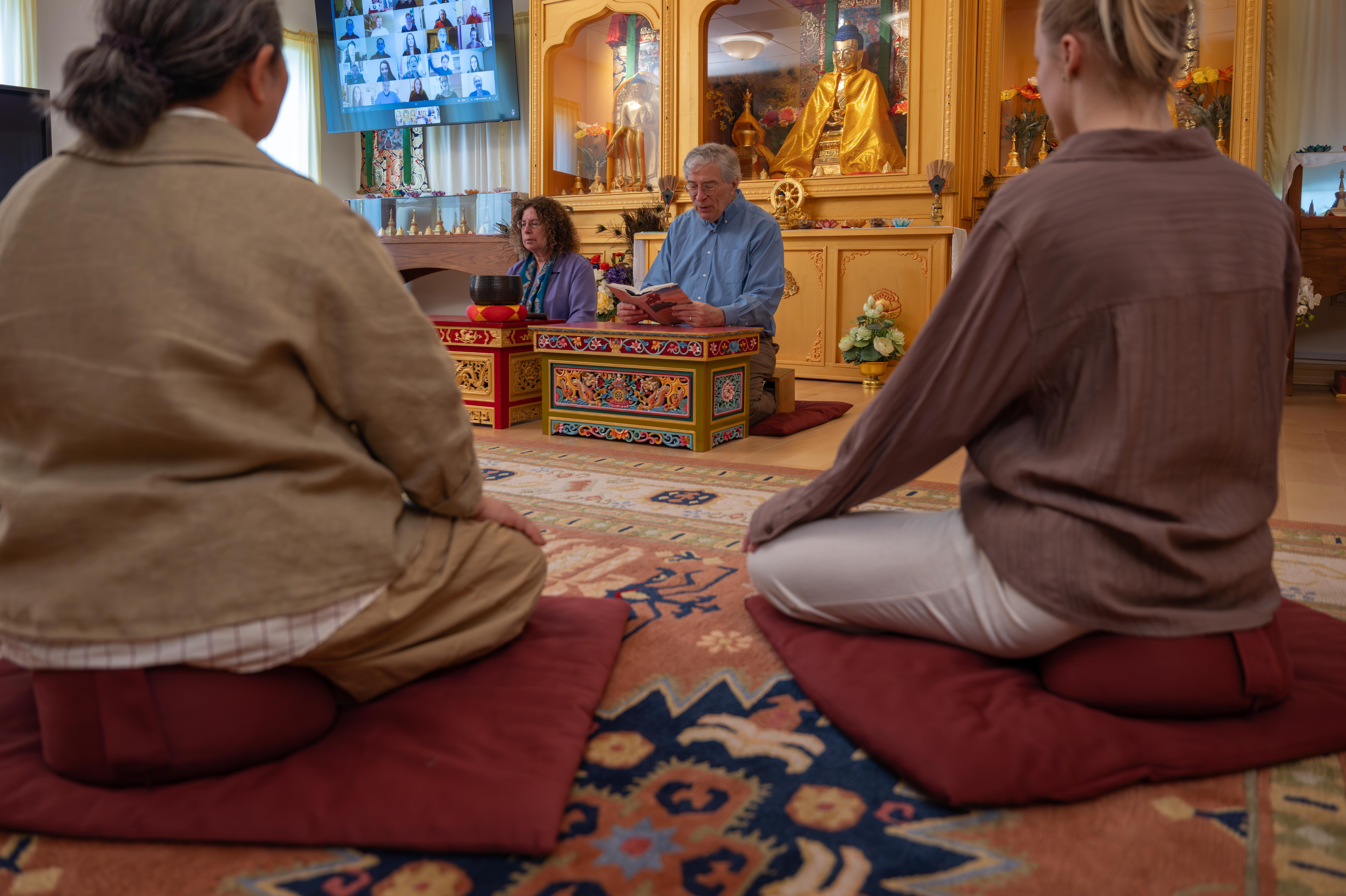 People meditating and praying in a Buddhist temple setting.