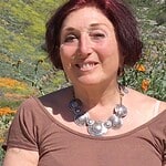 Woman with short red hair smiling in a field of orange and yellow flowers.