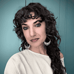 Close-up portrait of a woman with curly dark hair and earrings.