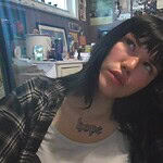 Person with black hair and plaid shirt in a cozy room.