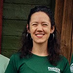 Smiling woman in green T-shirt at Foundation for Intentional Community event.