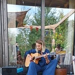 Young woman playing acoustic guitar outside during daytime.