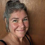 Smiling woman with gray hair and blue eyes, close-up portrait.