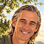 Smiling man outdoors with trees and sky in background.