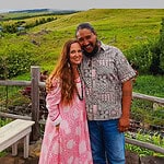 Couple standing together on a hilltop at a rustic outdoor venue.