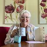 Smiling woman holding a mug with empowering message at community event.