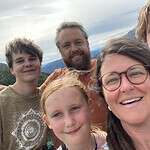 Family taking a selfie with mountain landscape in the background.