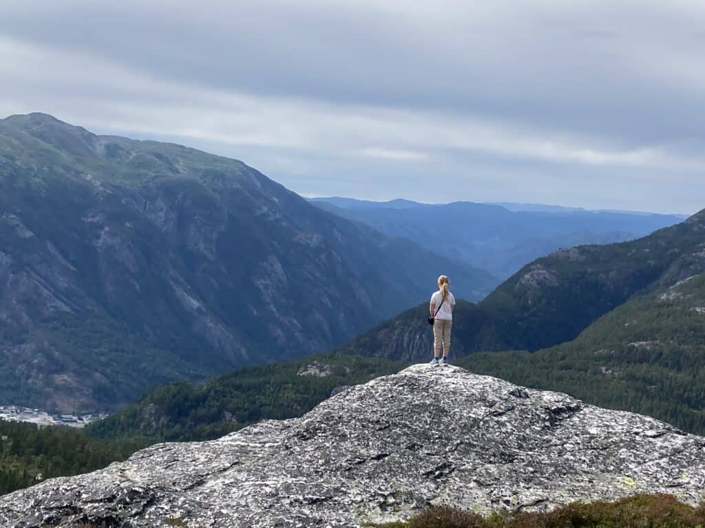 Hiker standing on a rock overlooking mountains and valleys.