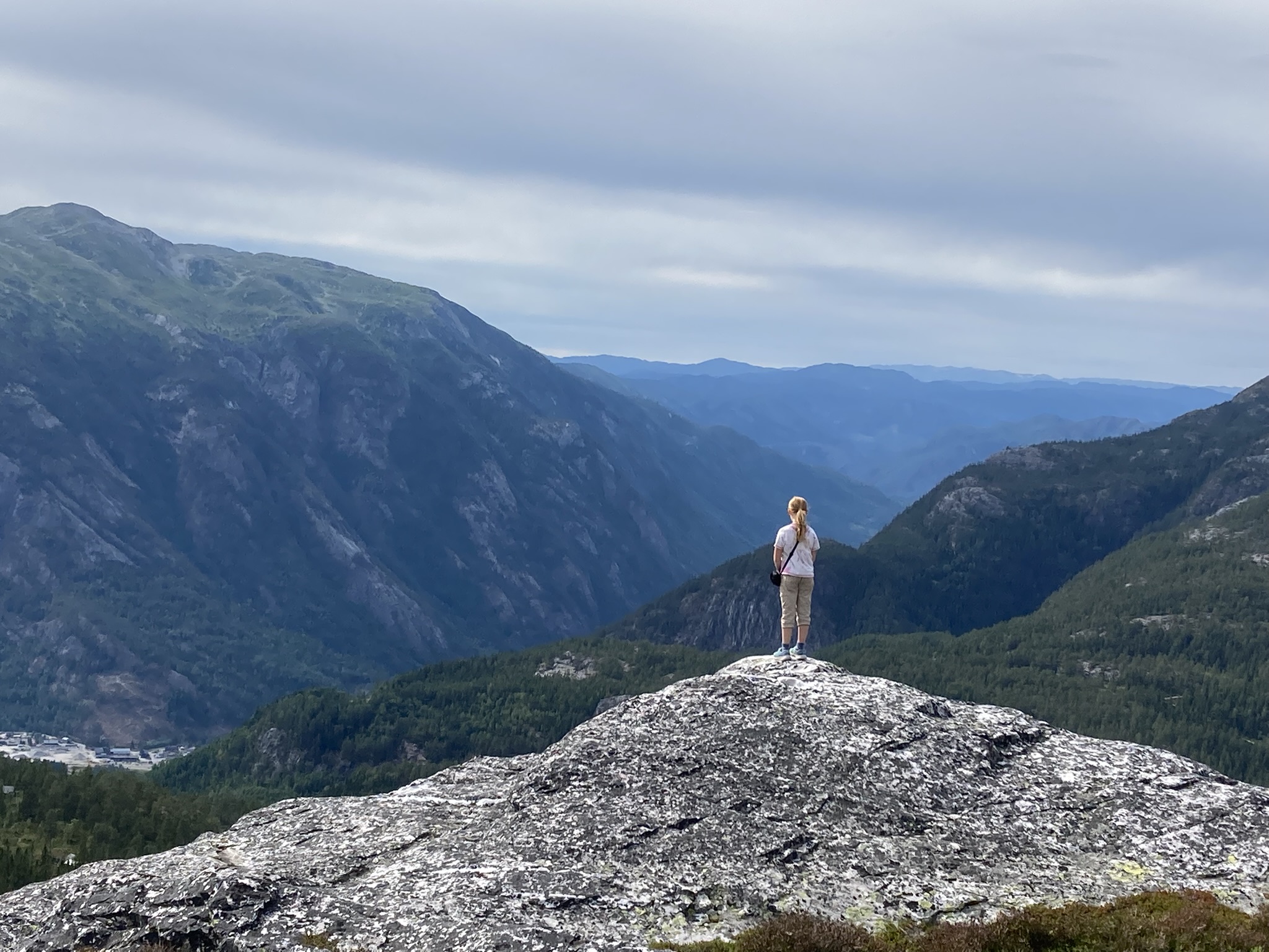 Hiker standing on a rock overlooking mountains and valleys.
