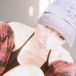 Woman wearing a gray cap and black top, taking a casual selfie.
